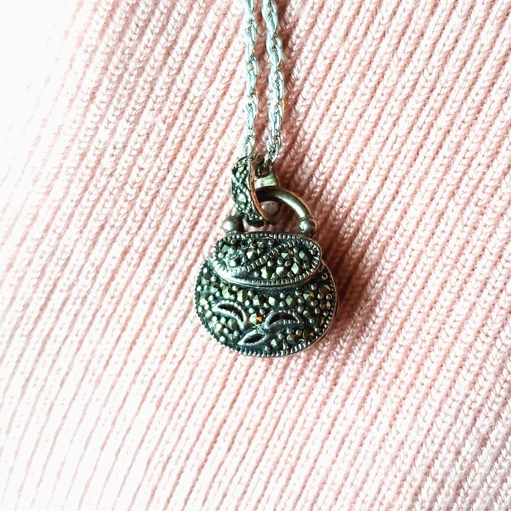 Purse-shaped pendant with opening top.